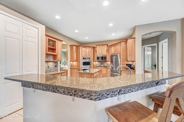 kitchen featuring a kitchen island, appliances with stainless steel finishes, a kitchen breakfast bar, and kitchen peninsula