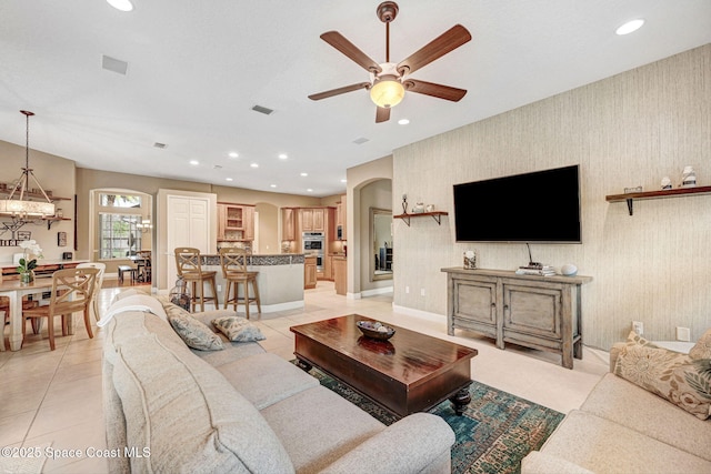 tiled living room featuring ceiling fan with notable chandelier