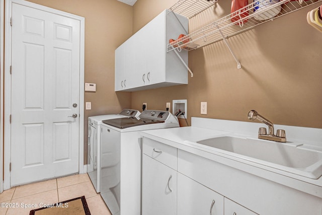 laundry area featuring cabinets, light tile patterned flooring, sink, and washer and clothes dryer