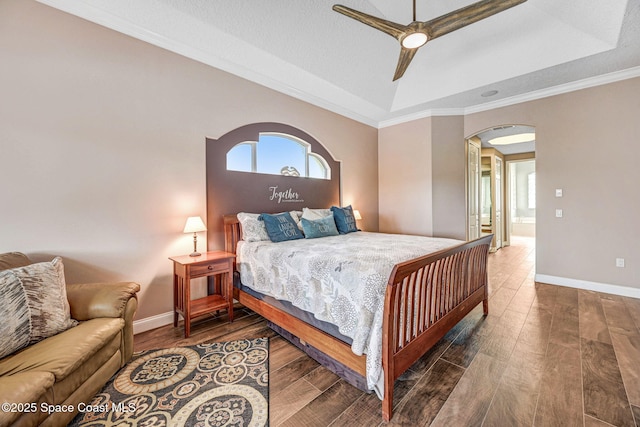 bedroom featuring dark hardwood / wood-style flooring, a tray ceiling, ornamental molding, and ceiling fan