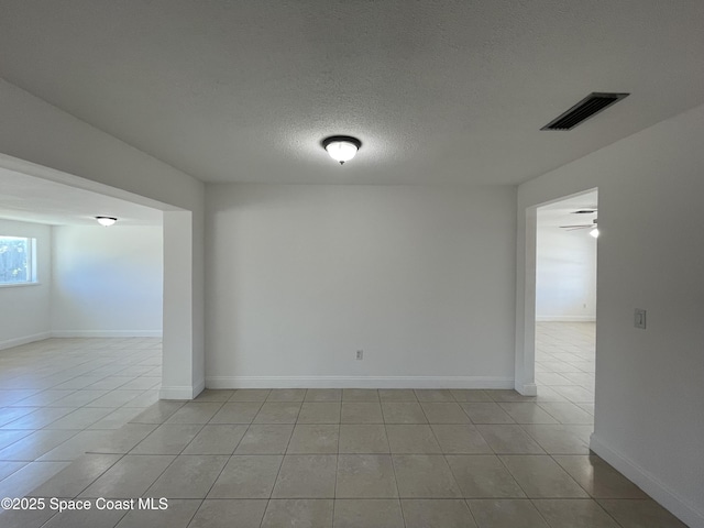 empty room featuring light tile patterned flooring, ceiling fan, and a textured ceiling