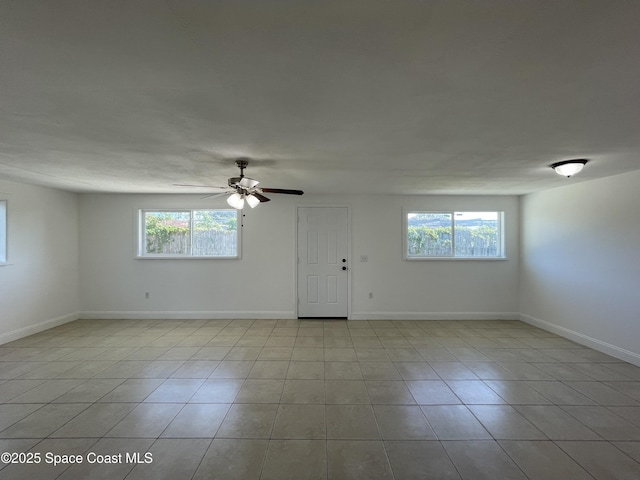 spare room featuring ceiling fan, a healthy amount of sunlight, and light tile patterned floors