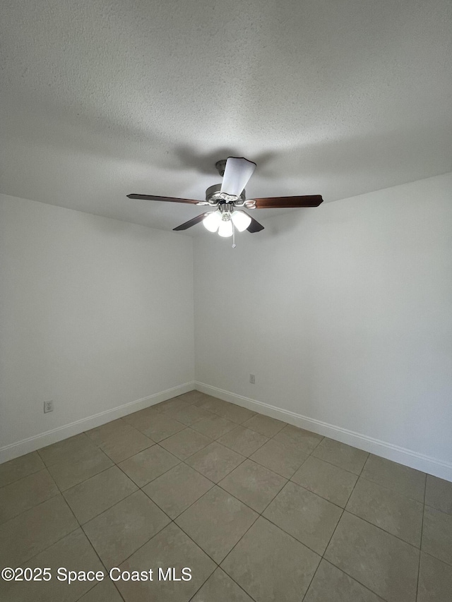 tiled empty room with ceiling fan and a textured ceiling