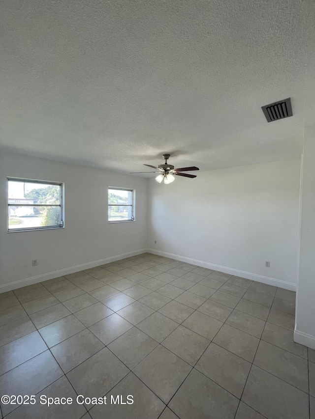 spare room featuring ceiling fan, a textured ceiling, and light tile patterned floors