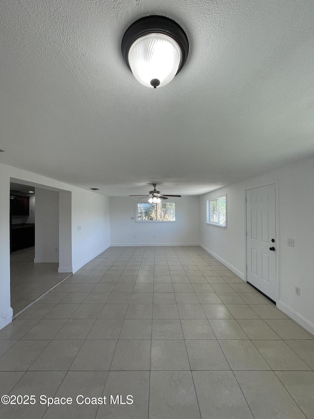 interior space featuring light tile patterned floors, a textured ceiling, and ceiling fan