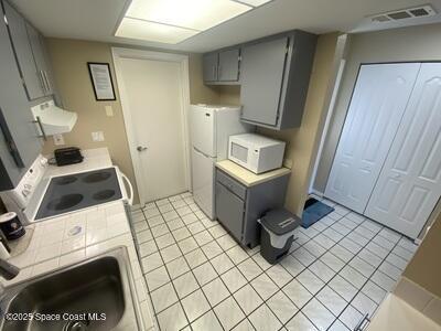 kitchen featuring white appliances, light tile patterned floors, visible vents, and gray cabinets