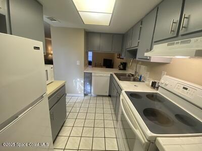 kitchen with gray cabinets, white appliances, and under cabinet range hood