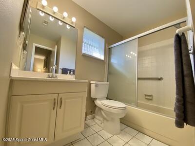 full bathroom with tile patterned flooring, enclosed tub / shower combo, vanity, and toilet