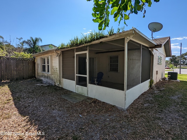 view of home's exterior featuring fence, a sunroom, and central air condition unit