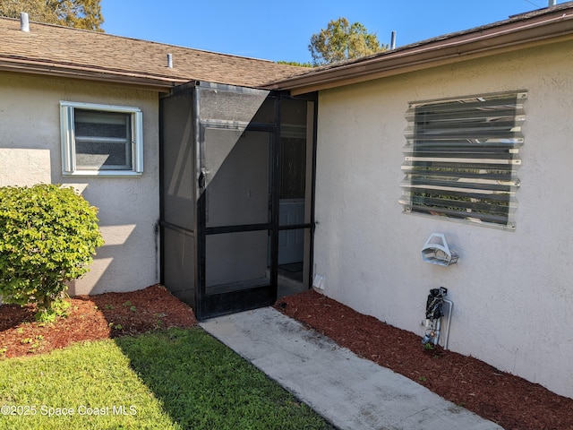 property entrance featuring a shingled roof and stucco siding