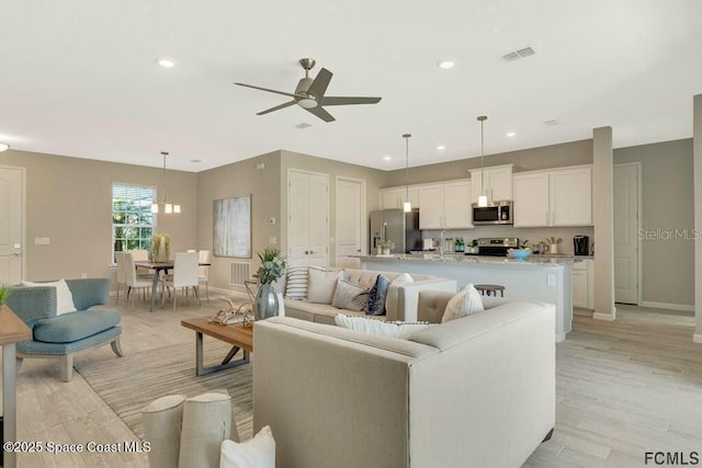 living room with baseboards, visible vents, ceiling fan, light wood-type flooring, and recessed lighting