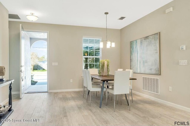 dining room featuring baseboards, visible vents, a notable chandelier, and light wood finished floors