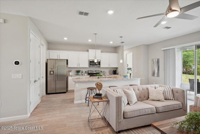 living area featuring light wood finished floors, visible vents, and recessed lighting