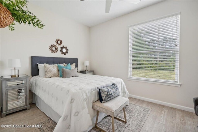 bedroom with baseboards, ceiling fan, and light wood-style floors