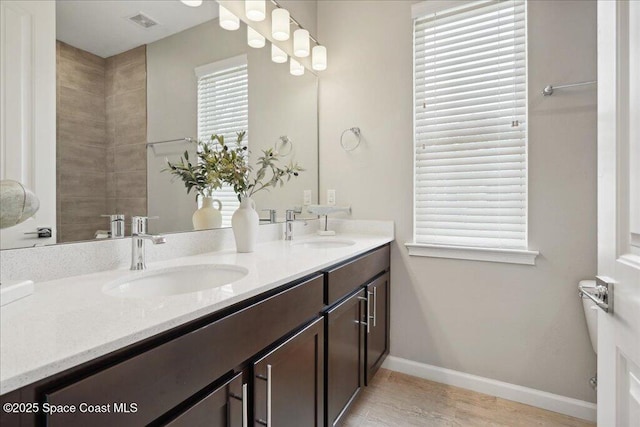 full bath featuring visible vents, a sink, baseboards, and double vanity