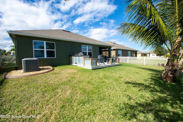 rear view of property with a yard, central air condition unit, and an outdoor kitchen