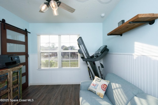 interior space featuring a barn door, dark hardwood / wood-style floors, a textured ceiling, and ceiling fan