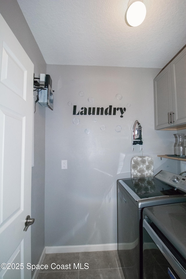 washroom featuring dark tile patterned flooring, washer and clothes dryer, cabinets, and a textured ceiling