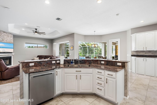 kitchen with sink, white cabinetry, decorative light fixtures, stainless steel dishwasher, and dark stone counters