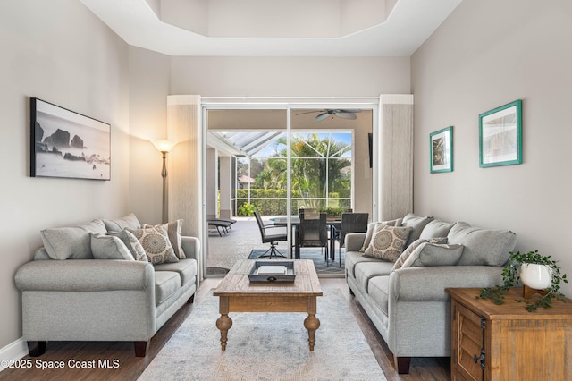 living room with dark wood-type flooring, ceiling fan, and a towering ceiling