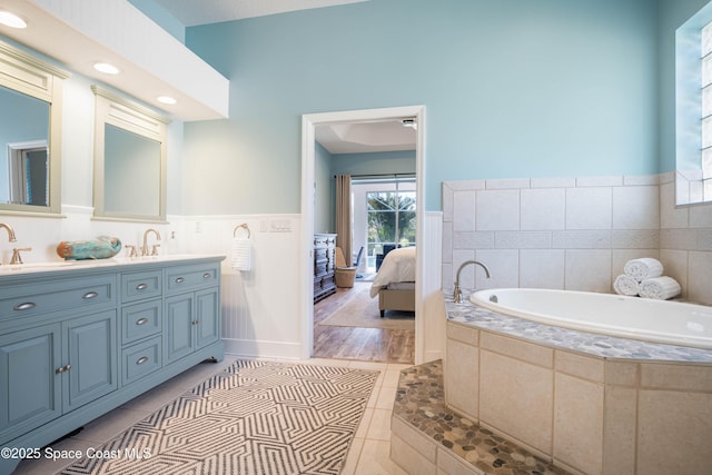 bathroom featuring a relaxing tiled tub, vanity, and tile patterned flooring