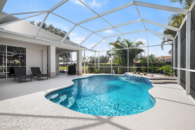 view of pool with pool water feature, glass enclosure, and a patio area