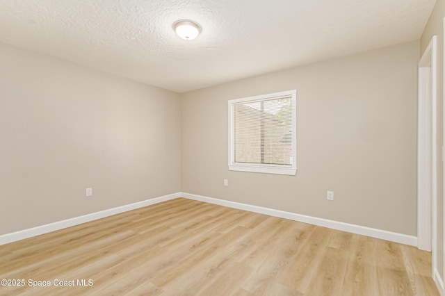 empty room with a textured ceiling and light wood-type flooring