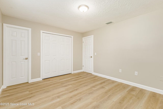 unfurnished bedroom with a closet, a textured ceiling, and light hardwood / wood-style flooring