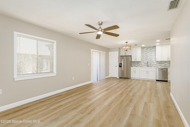 unfurnished living room with ceiling fan with notable chandelier, sink, and light wood-type flooring