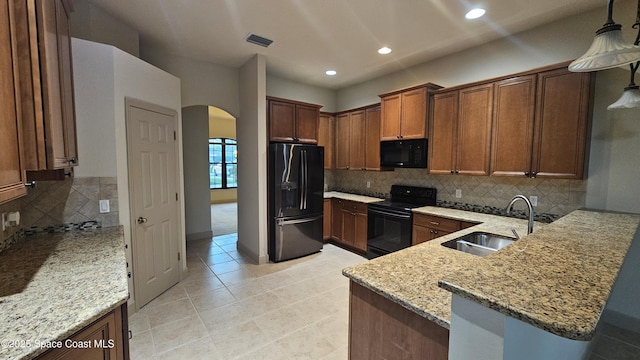 kitchen featuring sink, kitchen peninsula, light stone counters, and black appliances