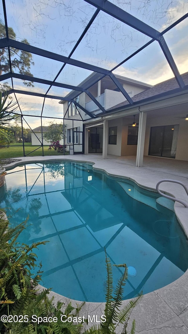 pool at dusk with a lanai and a patio