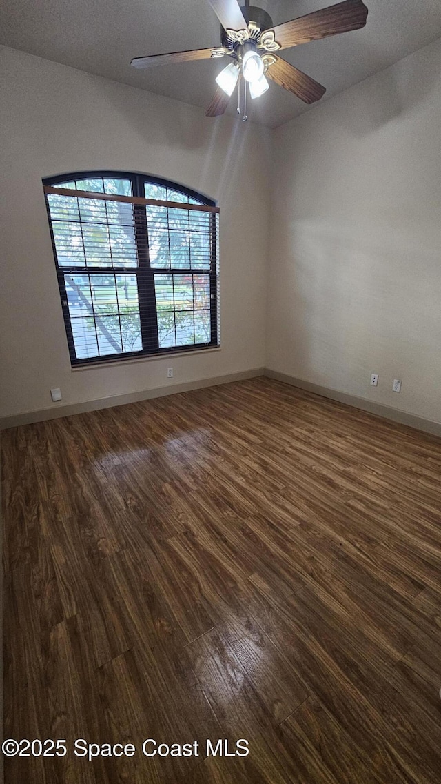 spare room featuring dark wood-type flooring and ceiling fan