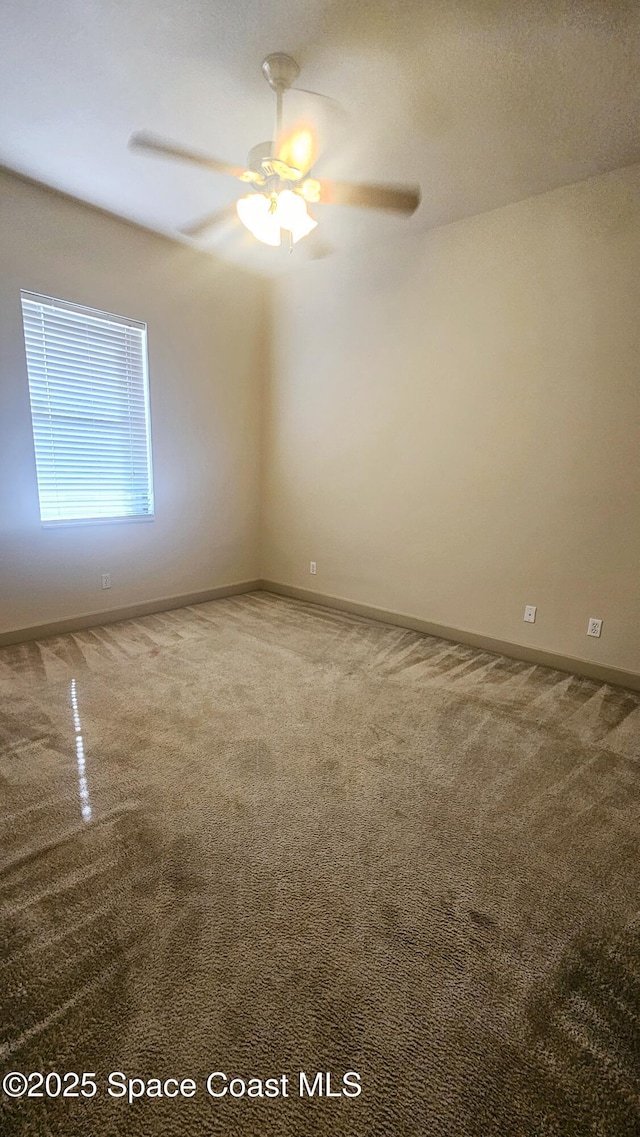 carpeted spare room featuring ceiling fan