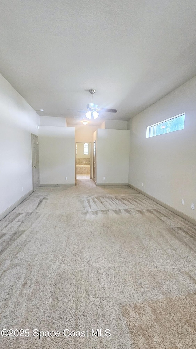 empty room featuring ceiling fan, light carpet, and a textured ceiling