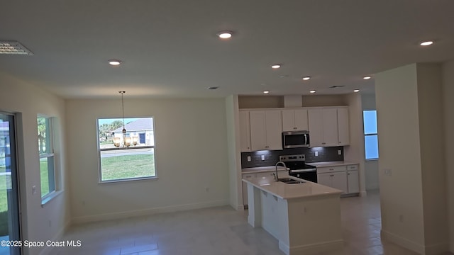 kitchen featuring electric range, an island with sink, white cabinets, pendant lighting, and backsplash