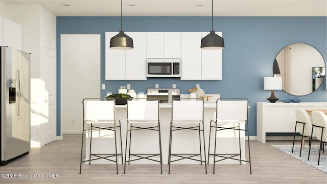 kitchen featuring white cabinetry, stainless steel appliances, decorative light fixtures, and light wood-type flooring