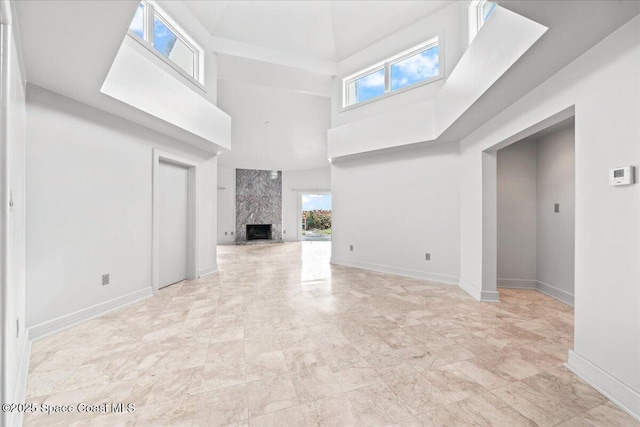 unfurnished living room with a fireplace and a high ceiling