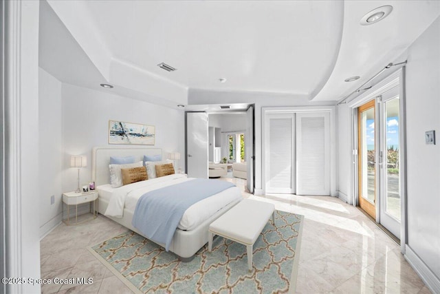 bedroom with a raised ceiling, two closets, and access to exterior