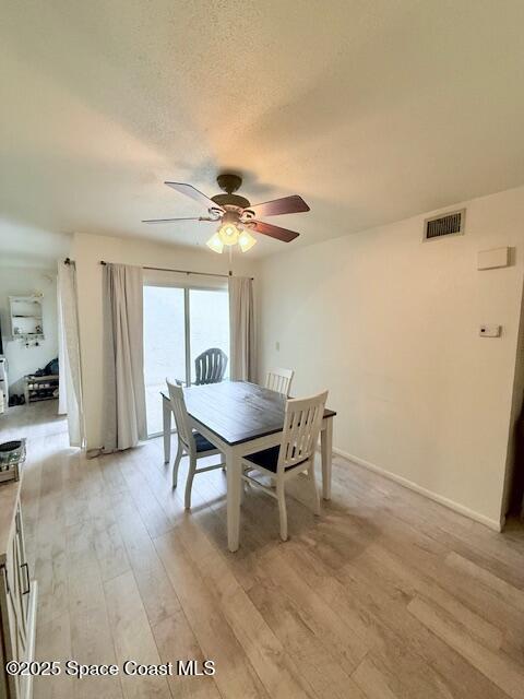 dining space featuring ceiling fan, a textured ceiling, and light hardwood / wood-style flooring