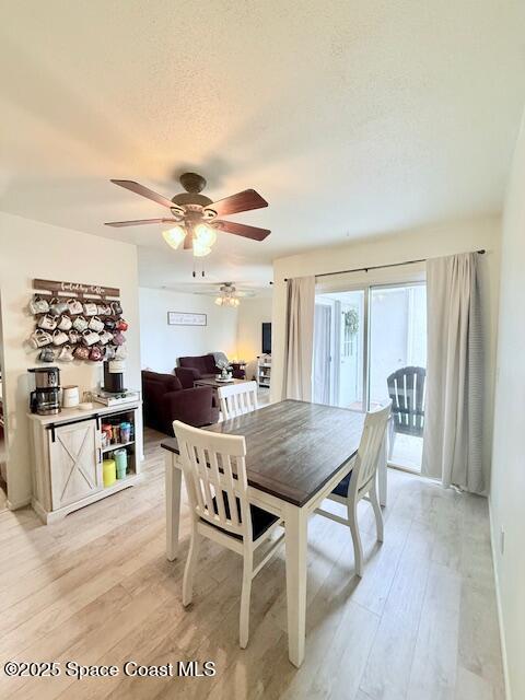 dining space featuring ceiling fan, light hardwood / wood-style flooring, and a textured ceiling