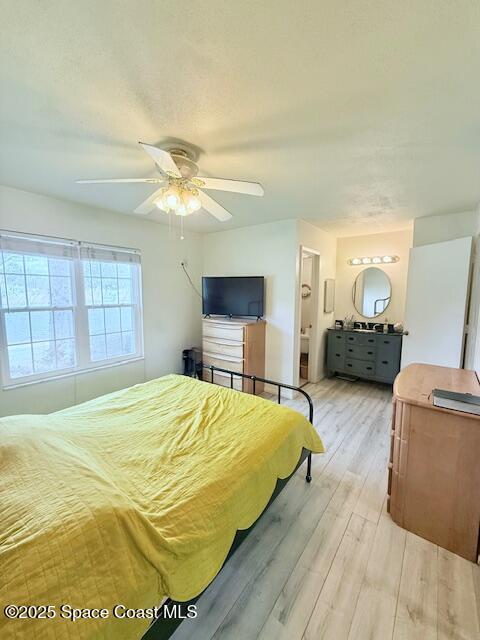 bedroom featuring ceiling fan, light hardwood / wood-style floors, and ensuite bath