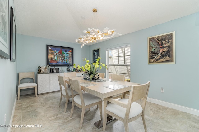 dining area featuring lofted ceiling and a notable chandelier