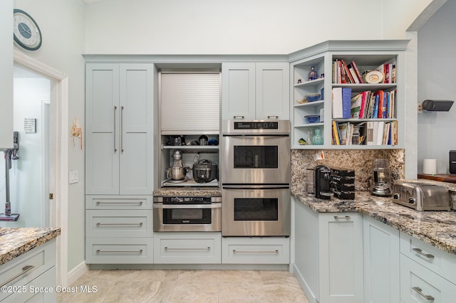 kitchen with light stone countertops, light tile patterned floors, backsplash, and double oven