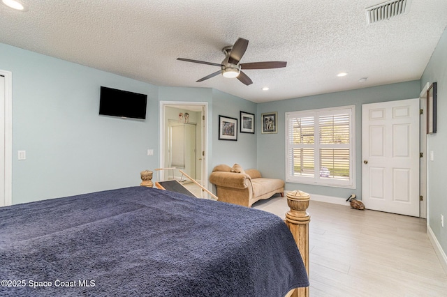 bedroom with a textured ceiling, ceiling fan, and light hardwood / wood-style flooring