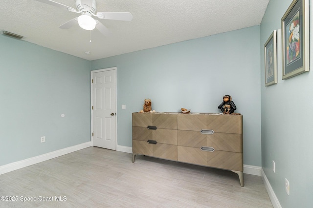 bedroom with ceiling fan, light hardwood / wood-style floors, and a textured ceiling