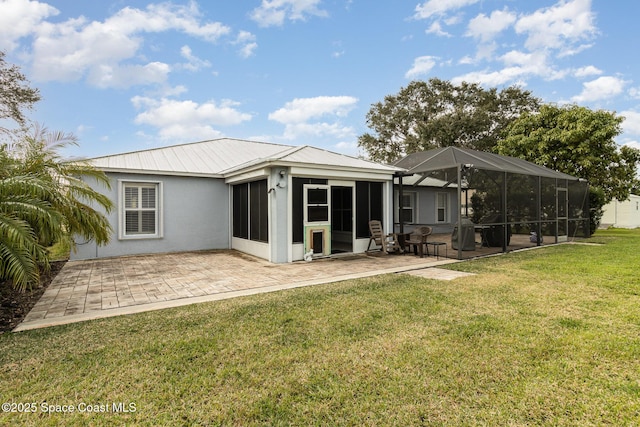 rear view of house featuring a lawn, glass enclosure, and a patio area