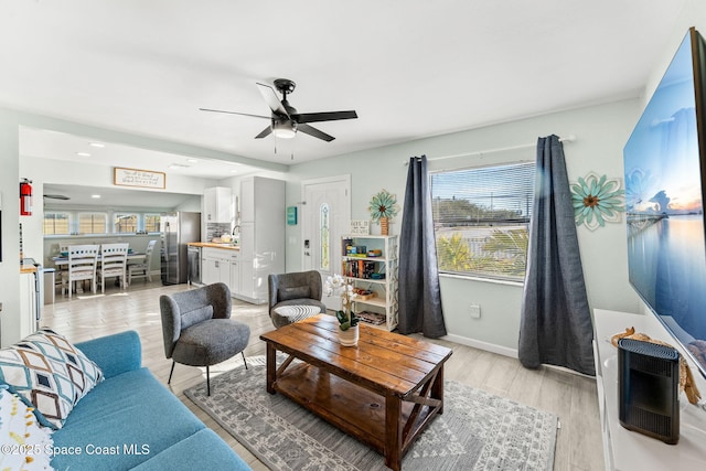 living room with light hardwood / wood-style flooring and ceiling fan