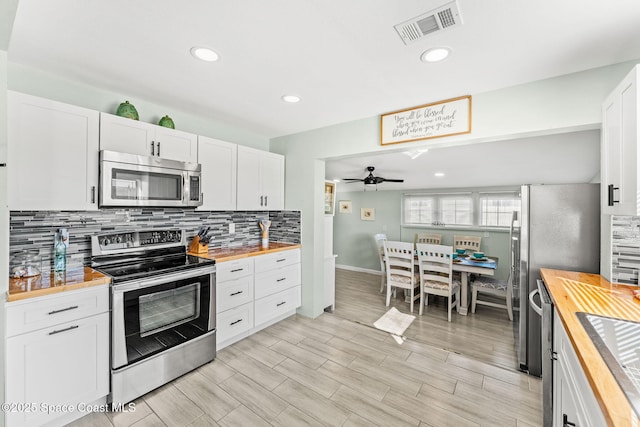 kitchen with white cabinets, wooden counters, decorative backsplash, ceiling fan, and stainless steel appliances