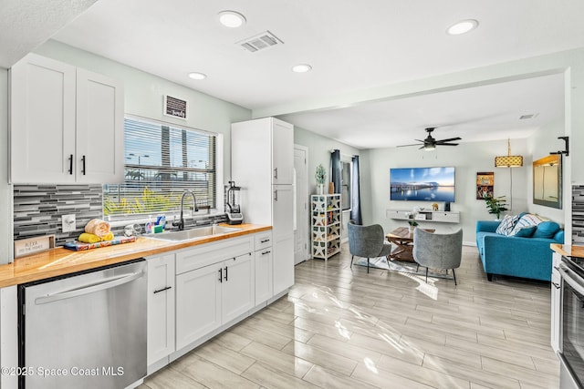 kitchen featuring sink, stainless steel dishwasher, white cabinets, and wood counters