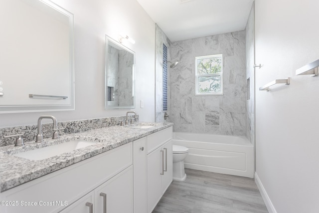 full bathroom featuring vanity, tiled shower / bath combo, wood-type flooring, and toilet